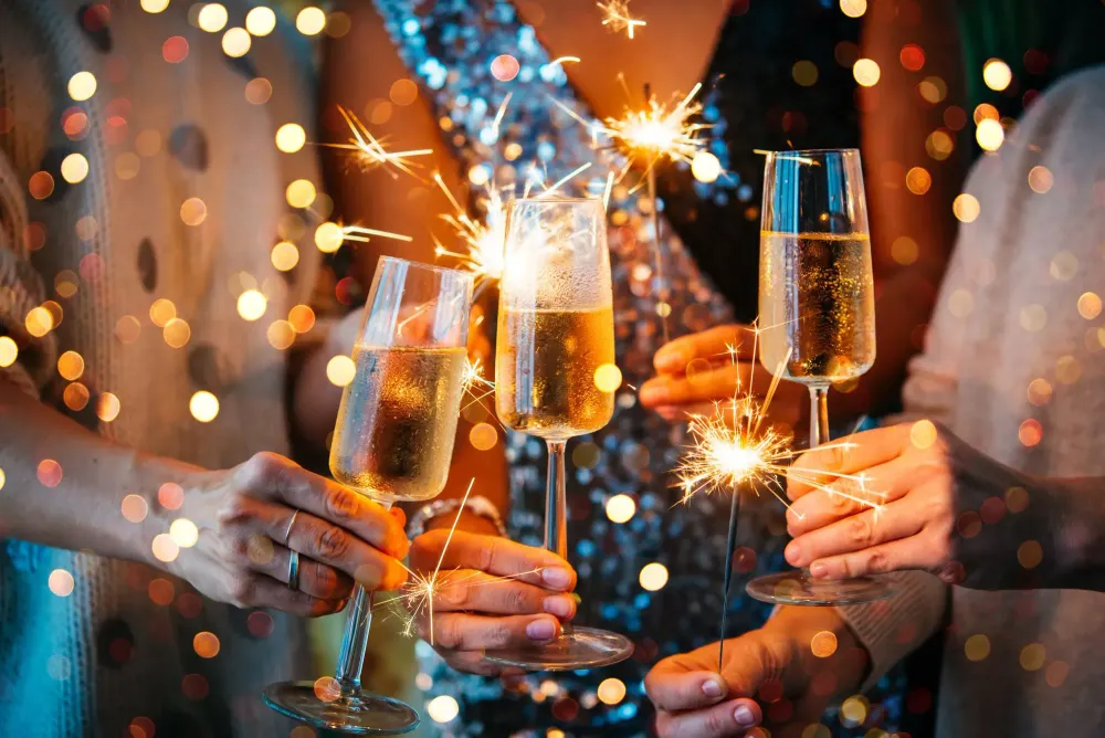 Close up of a champagne toast and people holding sparklers on New Year's Eve